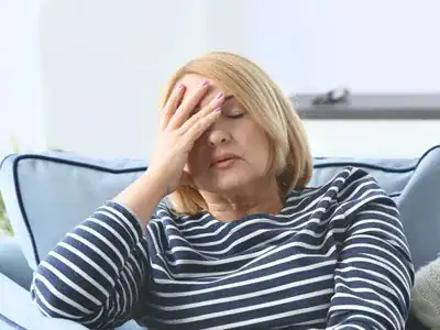 woman sitting with hand over face looking in pain
