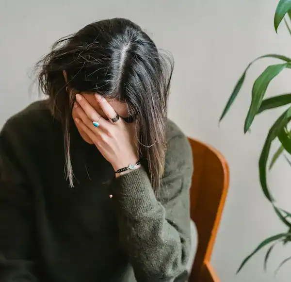 young woman sitting in chair with head in hand